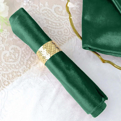 Green satin napkin with a gold ring on an elegant table setting.