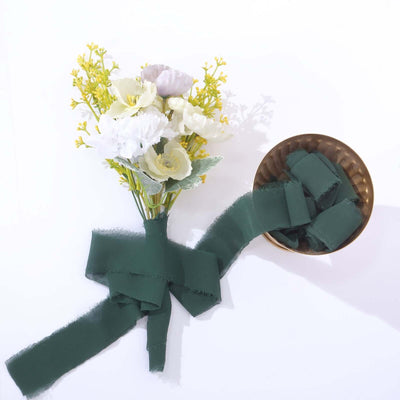 Floral bouquet with green ribbon on a gold bowl against a white background