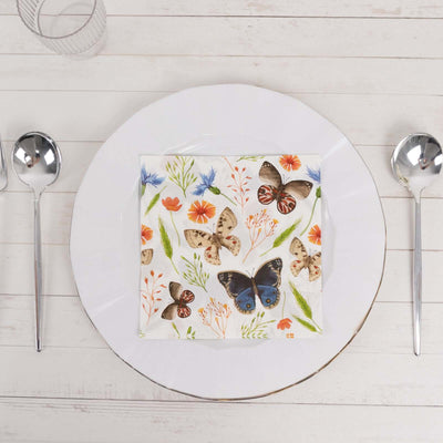 Butterfly-patterned napkin on a white plate with silver spoons