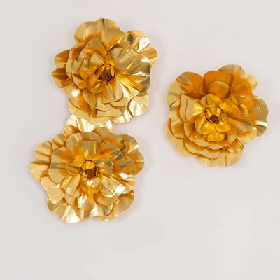 Three gold decorative flowers on a plain background.