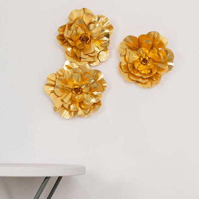 Gold paper flowers on a wall above a white table.