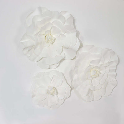 White paper flowers in varying sizes on a plain background