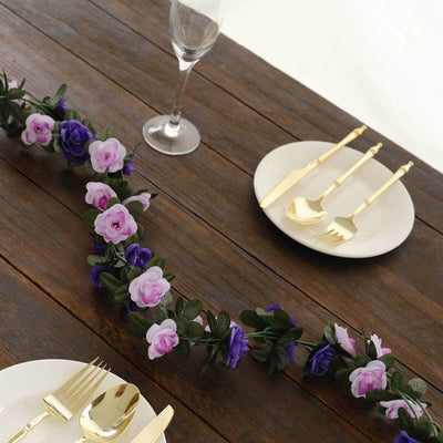 Elegant table setting with gold cutlery and floral garland on rustic wood.