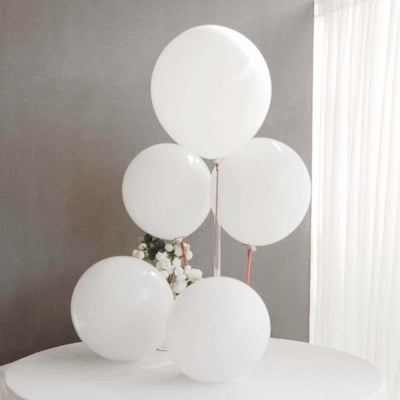 Five white balloons on a table against a gray background.