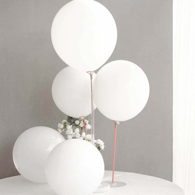 White balloons arranged elegantly on a table with a floral backdrop.