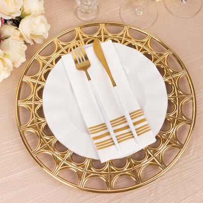 Elegant gold charger plate with white dinnerware and gold-accented utensils.