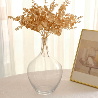 Clear glass vase with dried flowers on a table.
