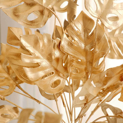 Gold monstera leaves arrangement in a decorative display.