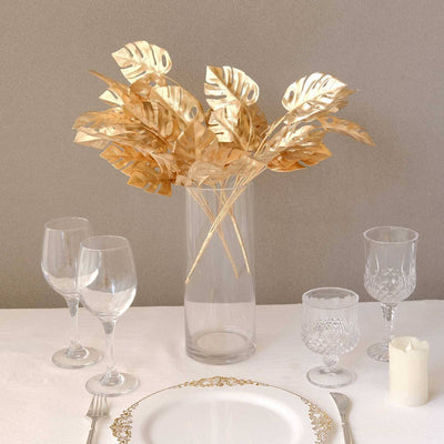 Gold leaf decorative arrangement in a clear vase on a dining table.