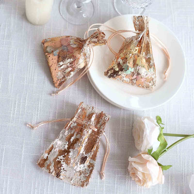 Decorative gift bags with colorful embellishments on a table setting.