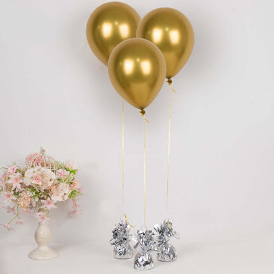 Three gold balloons tied with ribbons, surrounded by silver balloon weights.