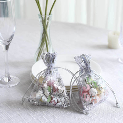 Decorative silver favor bags with colorful sweets on a dining table.