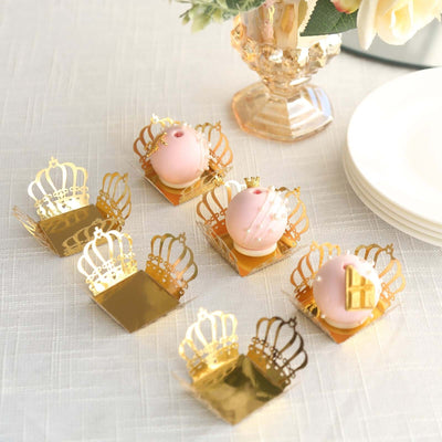 Decorative crown-shaped dessert holders with pink treats arranged on a table.