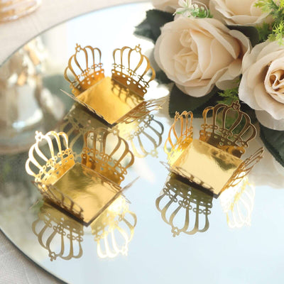 Golden crown-shaped dessert cups on a reflective surface with floral decor.