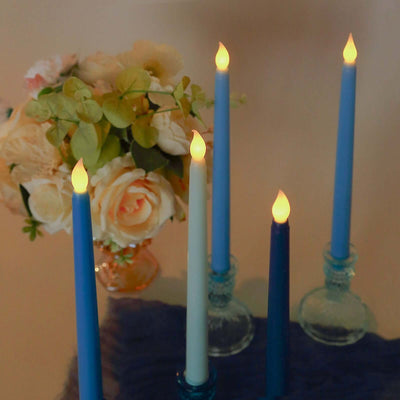 Colorful LED candles with floral arrangement in the background.