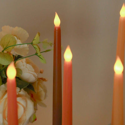 Colorful taper candles surrounded by decorative flowers.