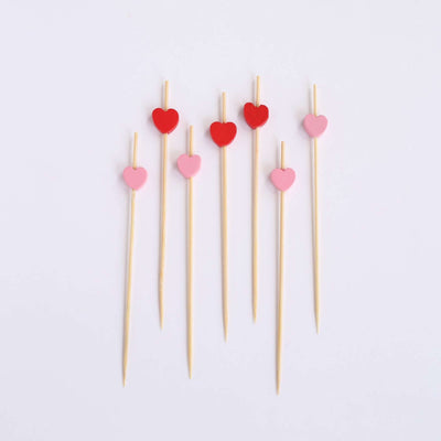 Heart-shaped cocktail picks in red and pink on a white background.