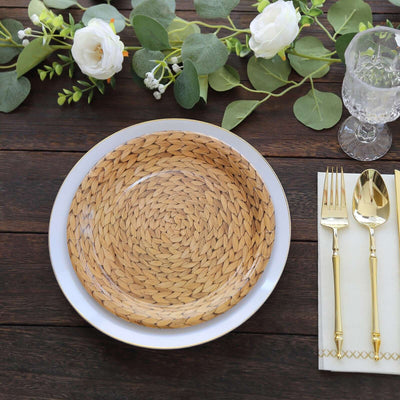 Woven rattan serving plate with elegant white rim and gold utensils on a wooden table.