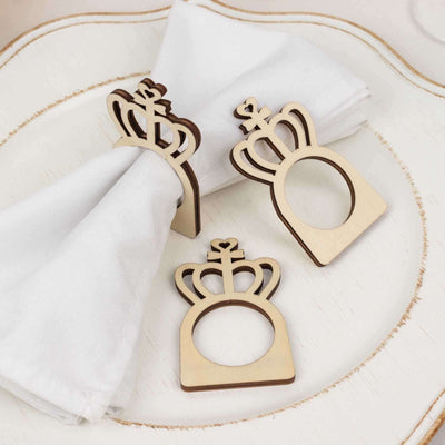 Wooden crown napkin rings on a decorative plate with a white napkin.