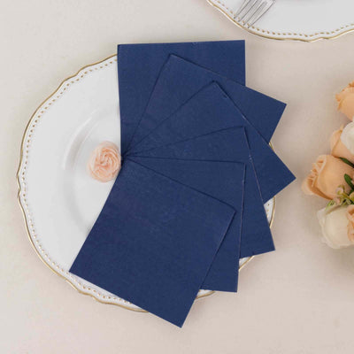 Navy blue place cards on a decorative plate with a flower accent.