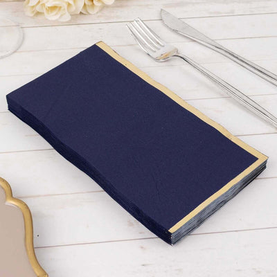 Navy blue napkins with gold trim on a white table setting.
