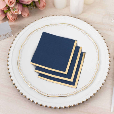 Navy blue cocktail napkins with gold trim on a decorative plate.