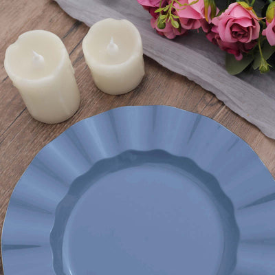 Blue scalloped plate with white candles and pink flowers on wooden table.