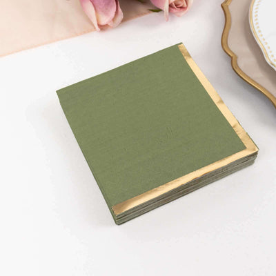 Green napkins with gold edges stacked on a table.