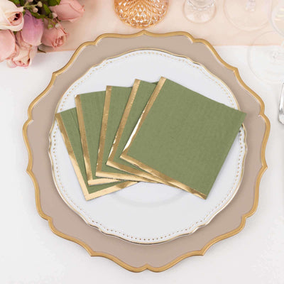 Green napkins with gold trim arranged on an elegant dinner plate.