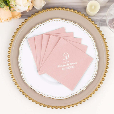 Personalized pink wedding napkins with names and date on a decorative plate.