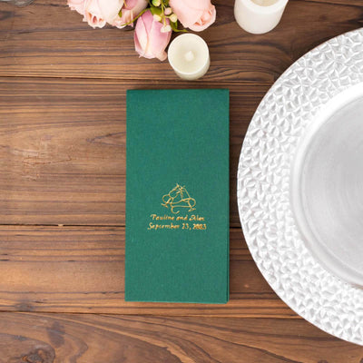 Green wedding invitation with gold lettering on wooden table.