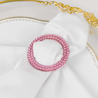 Pink beaded napkin ring on a white napkin with a gold-trimmed plate.