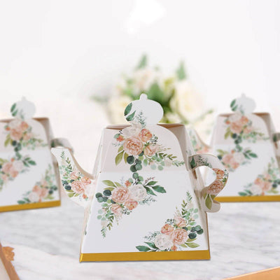 Floral teapot with a gold base on a white background.