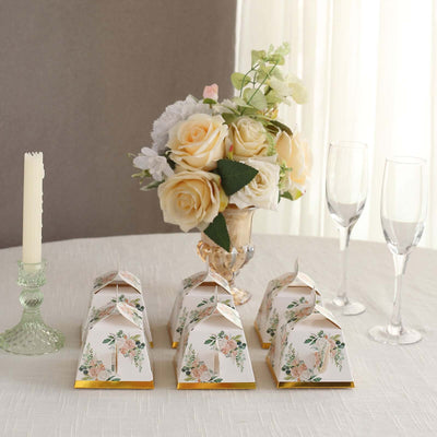 Elegant floral favor boxes arranged with a decorative vase and candles.