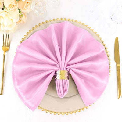 Elegant pink napkin with a decorative ring on a stylish plate setting.