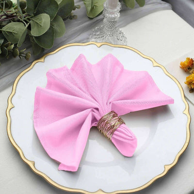 Pink napkin elegantly folded on a decorative plate with a gold rim.