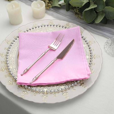 Pink napkin with silver cutlery on an elegant plate setting.