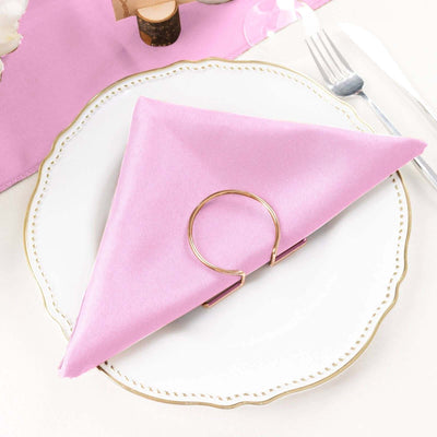 Pink napkin elegantly folded on a decorative plate with a gold napkin ring.