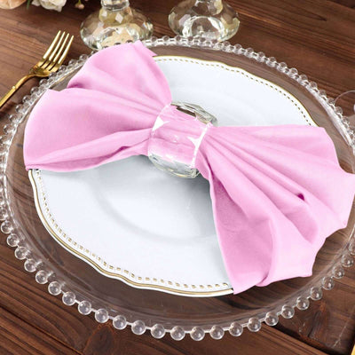 Pink napkin elegantly tied on a decorative plate with a crystal holder.