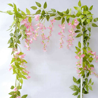 Artificial pink flower garland with green leaves on a white background.