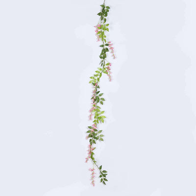 Artificial pink flower vine with green leaves on a plain background