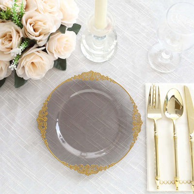 Elegant clear plate with gold trim, set on a textured tablecloth with floral centerpiece.