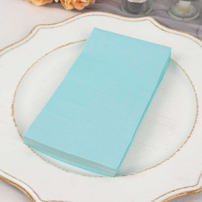 Light blue napkins stacked on a decorative white plate.