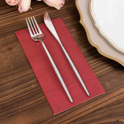 Silver fork and knife on a red napkin with decorative plate