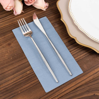 Silver fork and knife on a blue napkin with elegant tableware