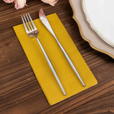 Silver fork and knife on a yellow napkin, set on a wooden table.