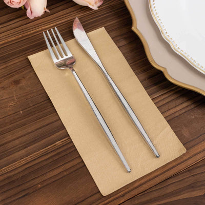 Silver fork and knife on a beige napkin, styled for dining.