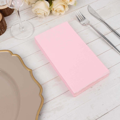 Pink disposable napkins stacked on a rustic table setting.