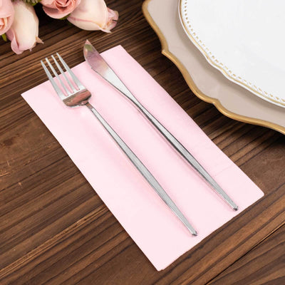 Silver fork and knife on pink napkin with elegant plate and floral backdrop.