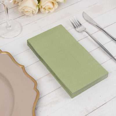 Green napkins stacked on a rustic table setting with cutlery.